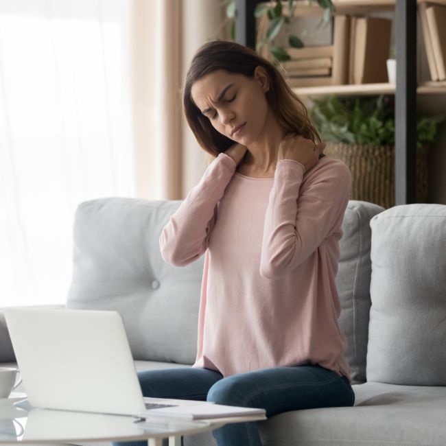 kobieta pracująca przed komputerem trzyma się za szyję