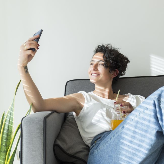 Osoba wykonuje selfie smartfonem, symbolizując wpływ mediów społecznościowych na samoocenę i porównywanie się z innymi.